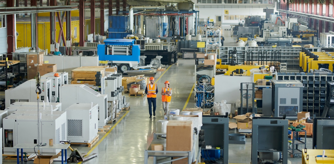 Two people in safety vests walking in a manufacturing facility